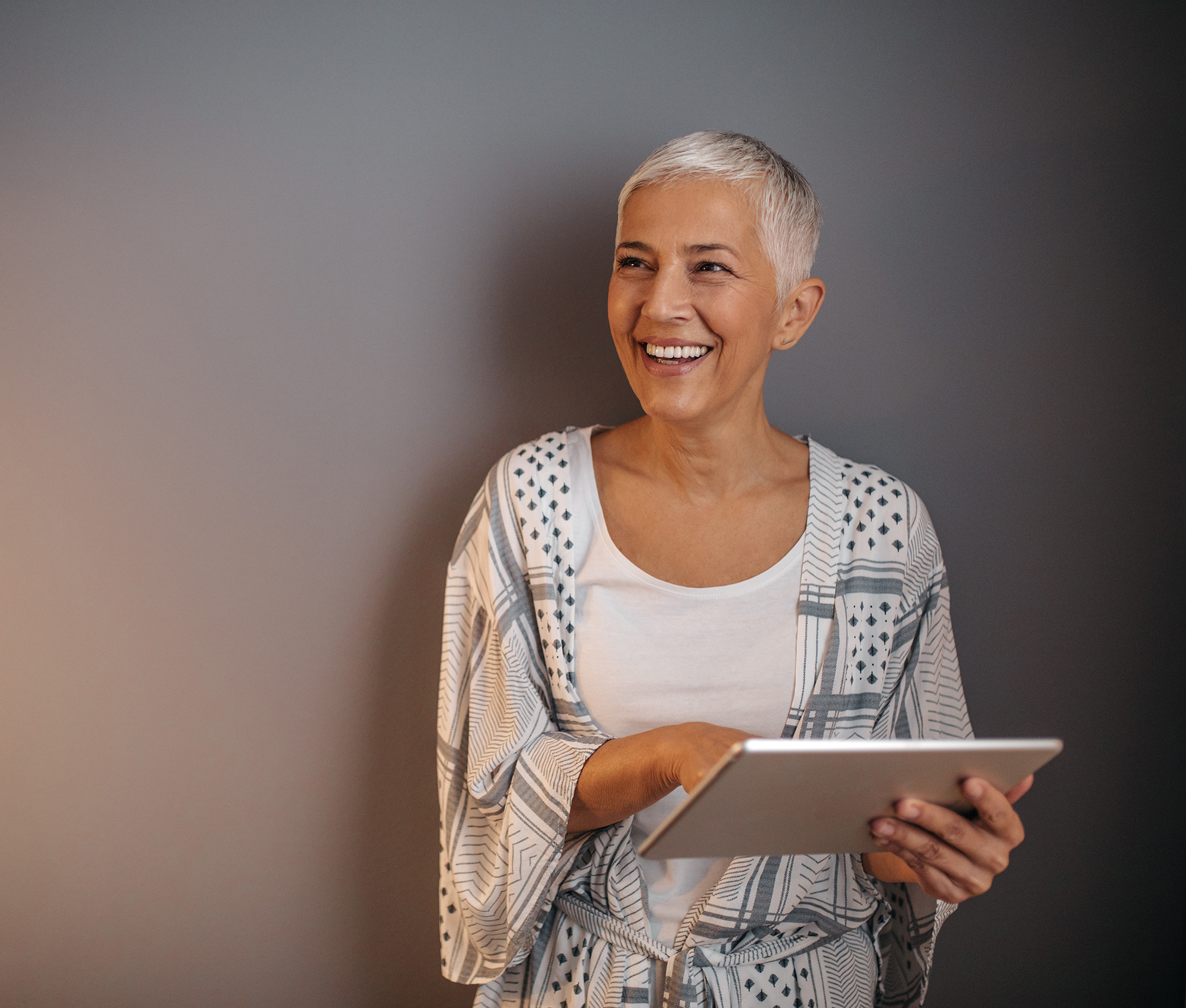 frau-graue-haare-mit-tablet-lacht-dunkler-hintergrund